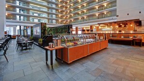 A modern hotel lobby with multiple dining areas, a central food station, and a high-ceiling atrium with balconies. - Embassy Suites by Hilton Chicago Downtown Magnificent Mile (Chicago)
