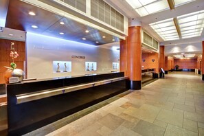 A hotel reception area with a modern design, featuring a black reception desk, a 'Concierge' sign, and a 'Stairs' sign indicating the direction to the street level. - Embassy Suites by Hilton Chicago Downtown Magnificent Mile (Chicago)