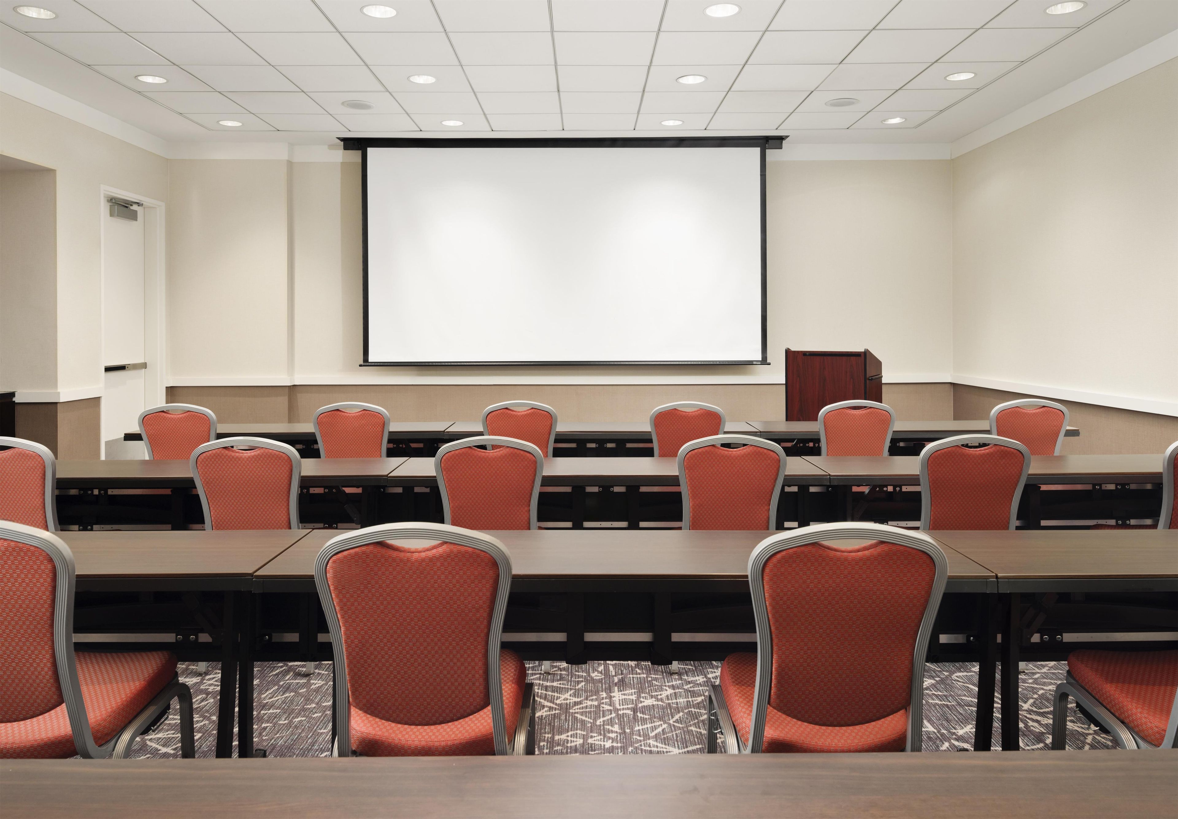 Une salle de conférence équipée d’un grand écran, de plusieurs tables et de chaises.