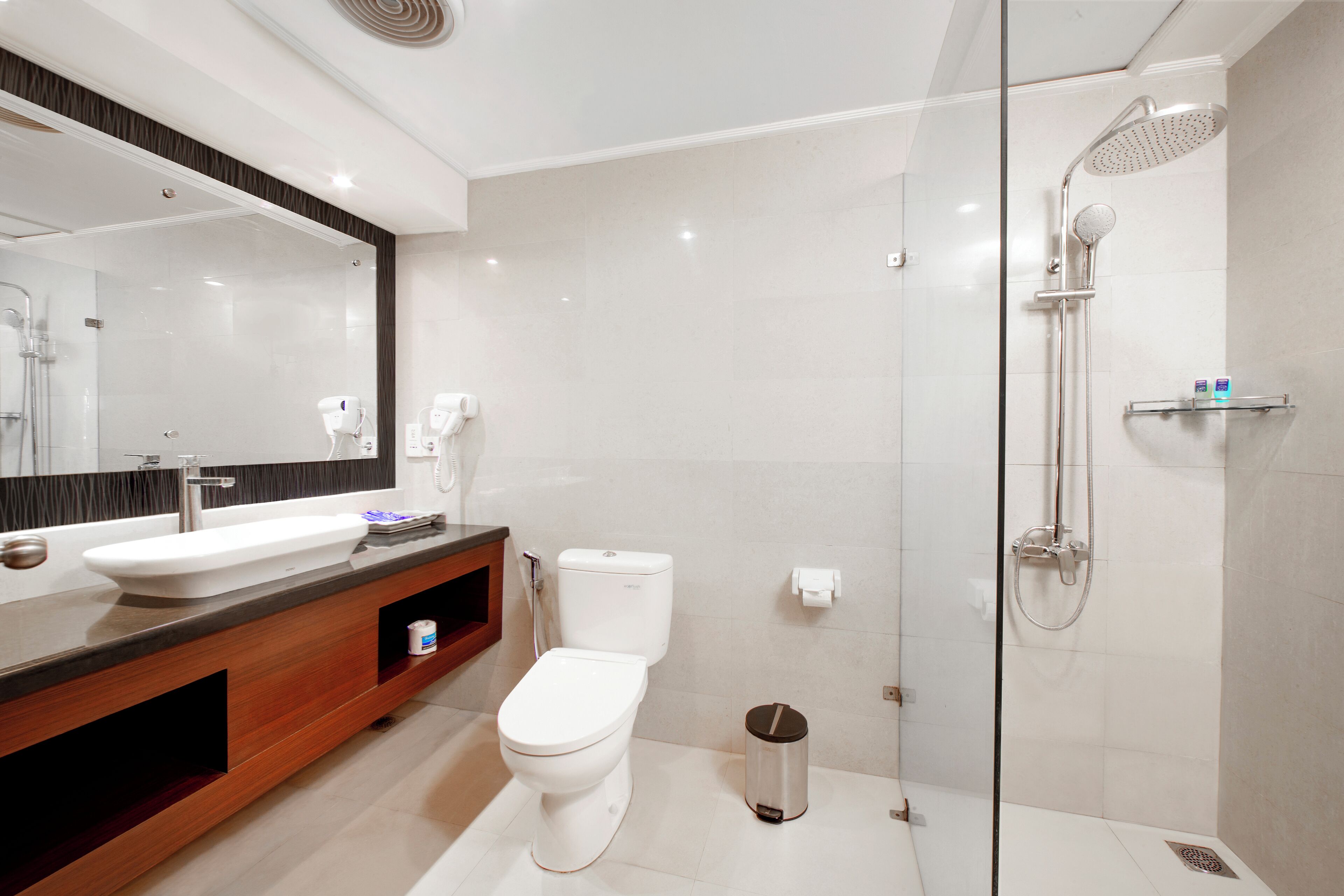 Un bagno moderno con doccia vetrata, un water bianco e un mobile lavabo con specchio.