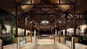 A spacious lobby with a high ceiling, stone columns, and a central chandelier. - Holiday Resort Lombok (Senggigi)