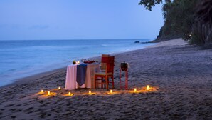 A beachside table set with candles, a tablecloth, and a chair, overlooking the ocean. - Holiday Resort Lombok (Senggigi)