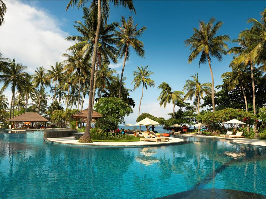 Una piscina al aire libre, sombrillas, sillones reclinables de piscina