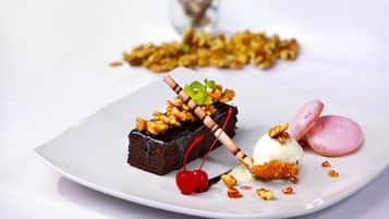 Un plato de postre con pastel de chocolate, cerezas y un macaron rosa.