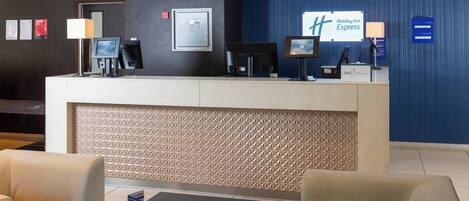 A hotel reception area with a modern design, featuring a reception desk, seating area, and a Holiday Inn Express sign.