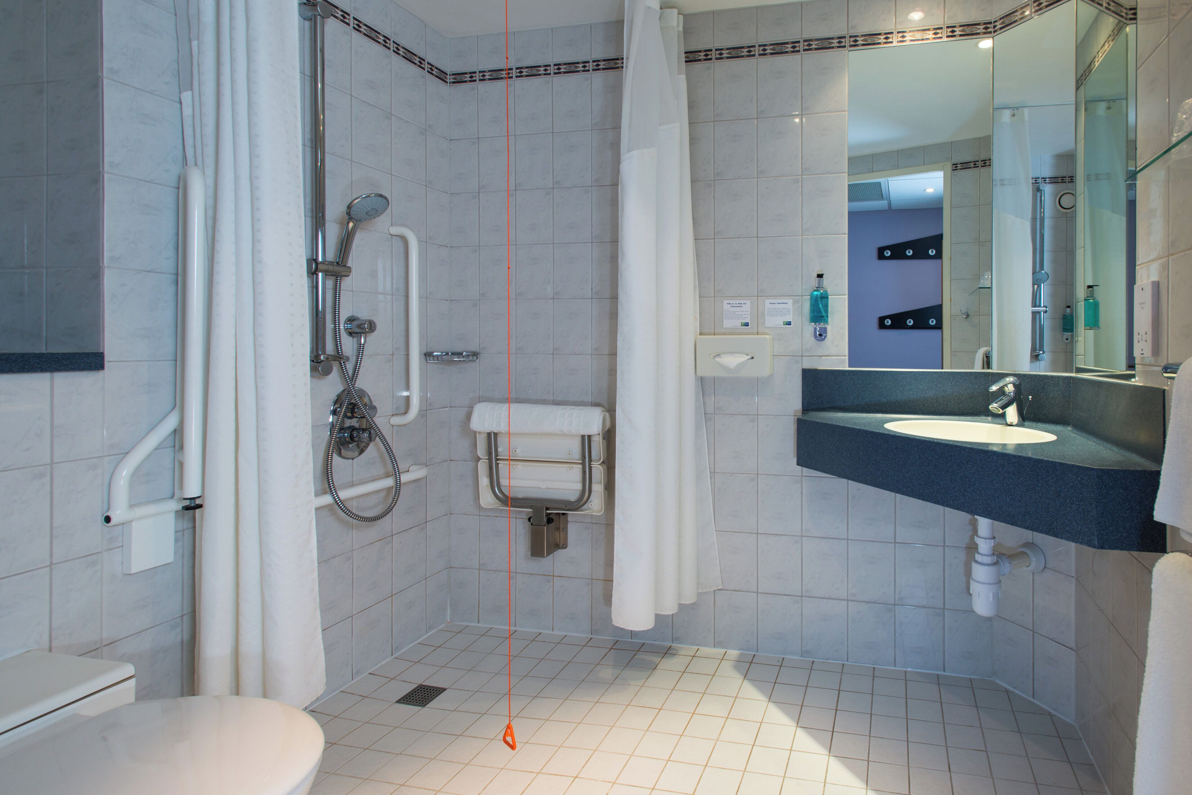 A modern bathroom with a shower, toilet, and sink.