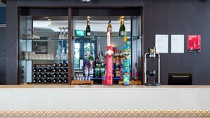 A bar area with shelves of bottles, a glass display case, and a counter with a coffee machine. - Holiday Inn Express London Wandsworth by IHG (London)