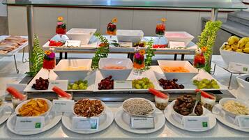 Buffet com diversos alimentos e bebidas, incluindo frutas, nozes e iogurte.
