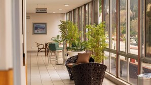 A corridor with wicker chairs, potted plants, and a sign indicating the direction to the Vumba room. - Holiday Inn Mutare by IHG (Mutare)