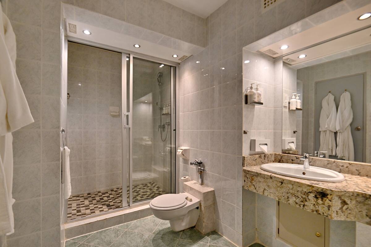 Un baño moderno con ducha envuelta en vidrio, un inodoro y un lavabo con encimera de mármol.