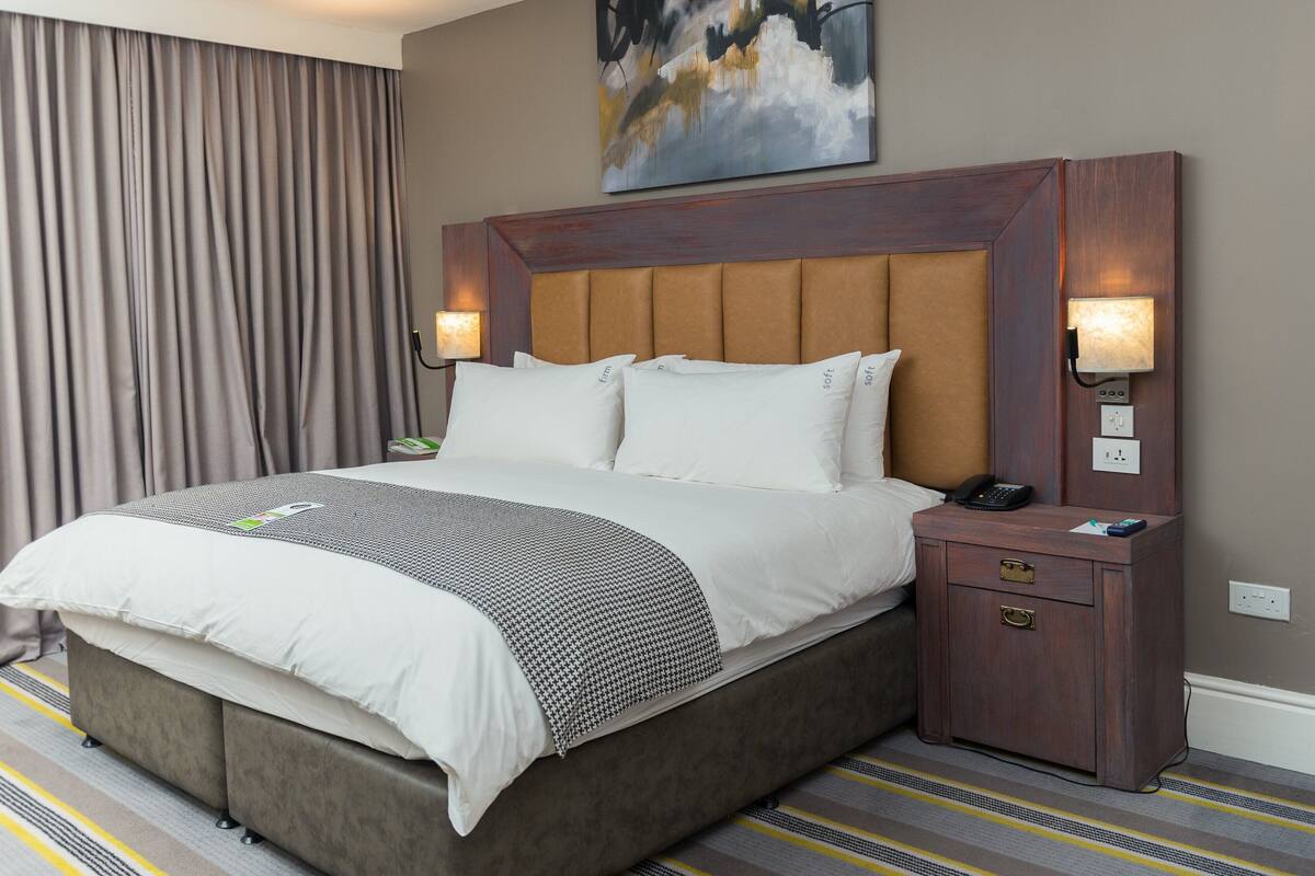 Habitación de hotel con una cama grande, una mesita de noche con un teléfono y un cuadro en la pared.