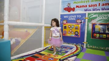 Children can play and learn in this engaging indoor play area featuring a colorful play mat and educational posters.