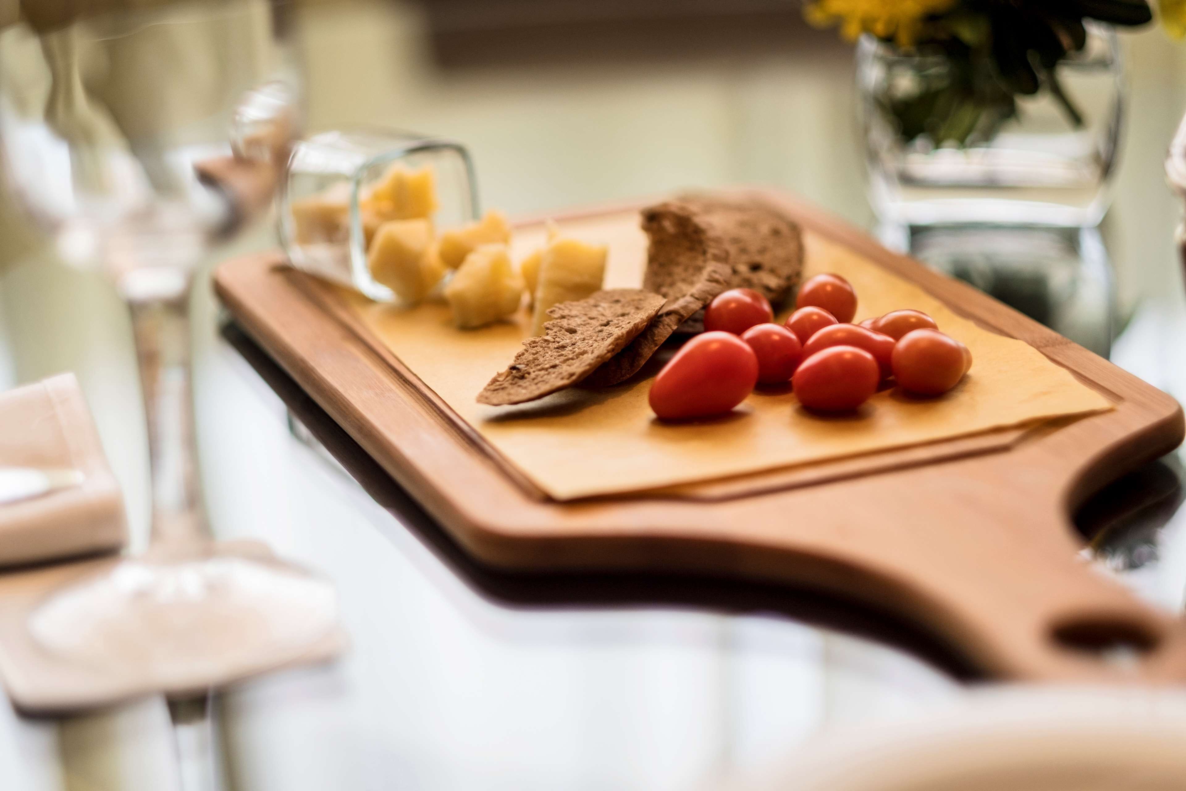 Una tabla de madera con rebanadas de pan, tomates cherry y cubos de queso.