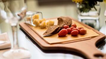 Una tabla de madera con rebanadas de pan, tomates cherry y cubos de queso.