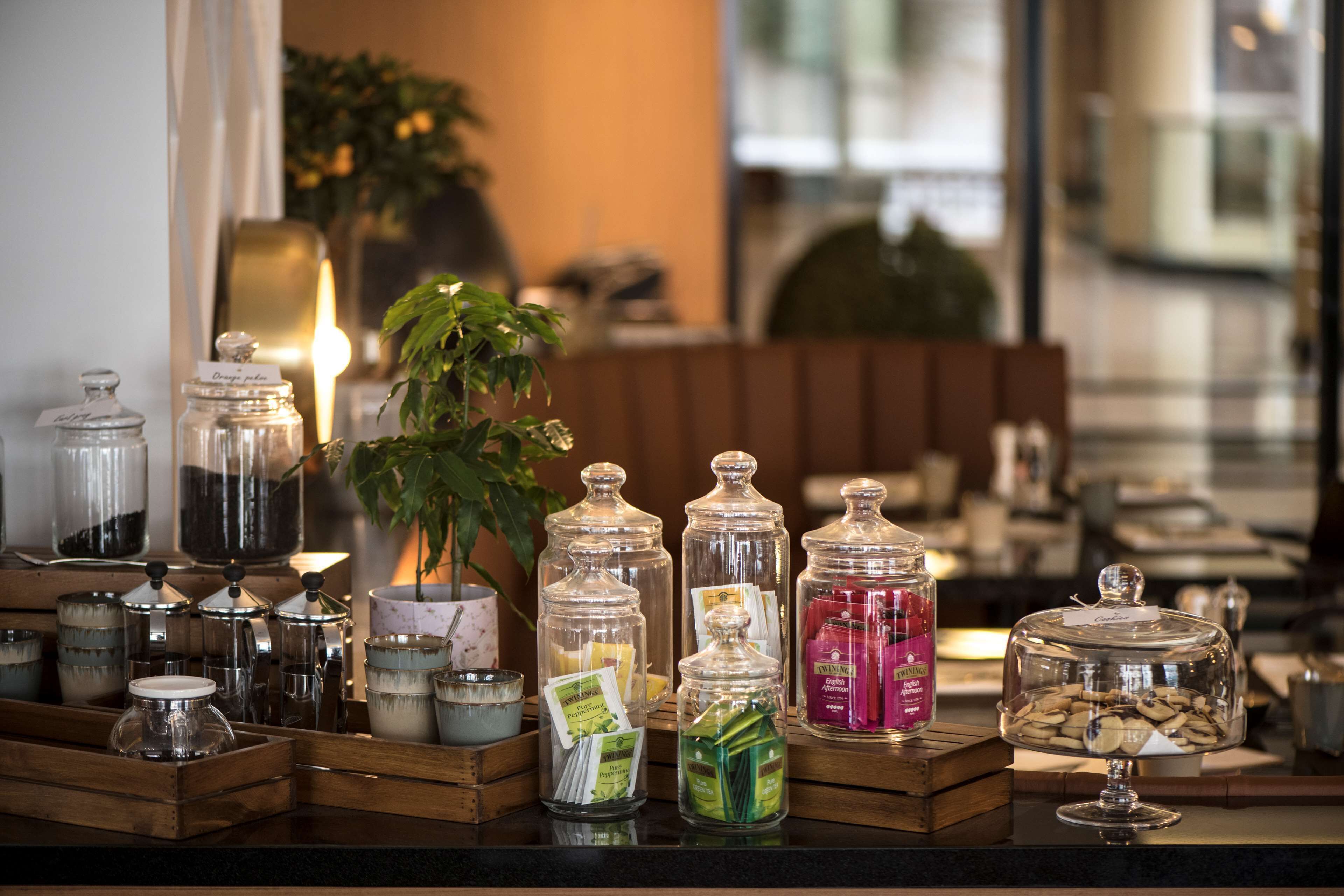 A variety of glass jars with lids, containing different food items, displayed on a wooden counter in a hotel setting.