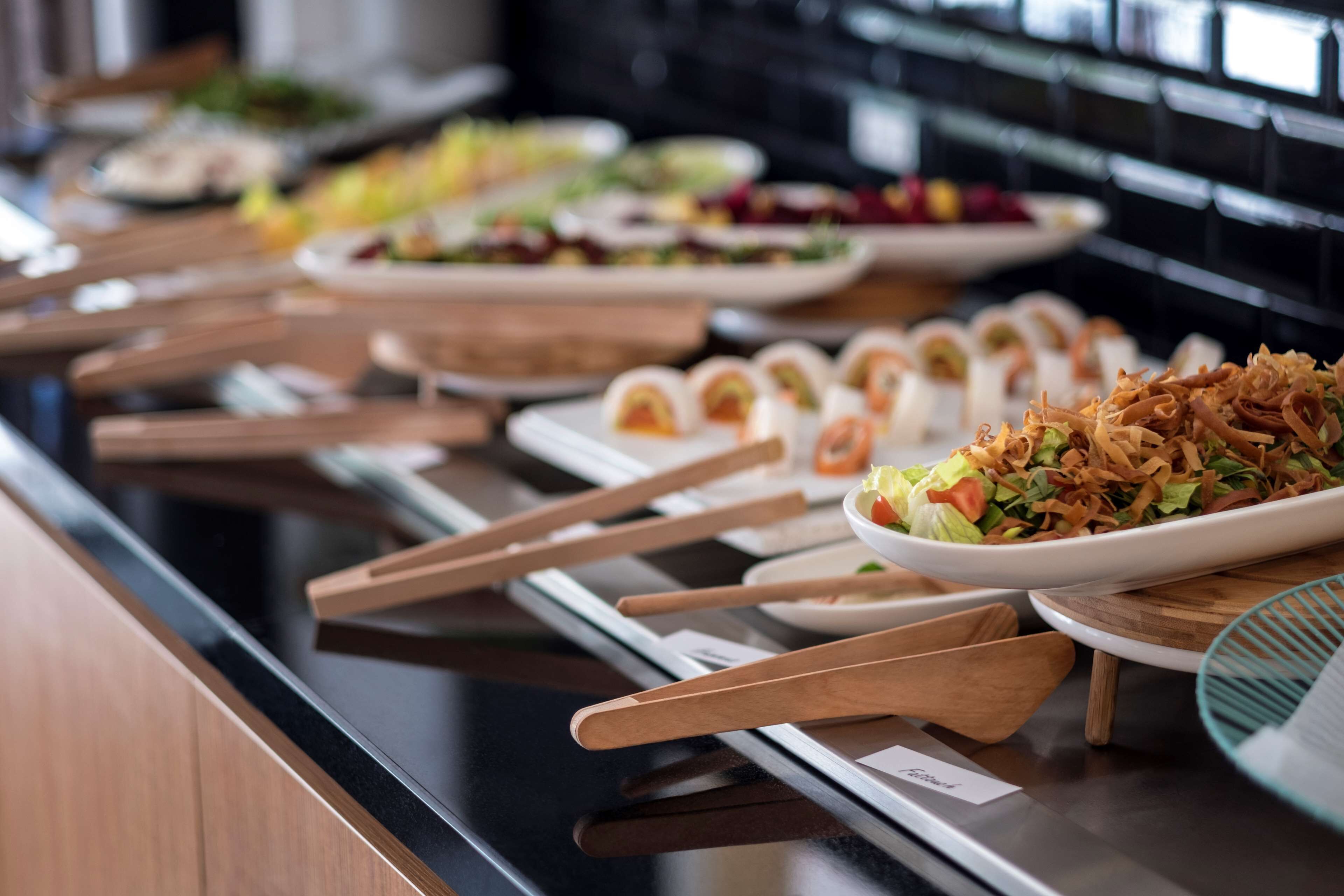 A buffet with various dishes and wooden serving utensils.