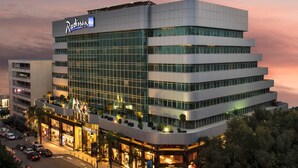 A modern hotel with a prominent 'Radisson' sign, multiple floors, and a central courtyard with seating.