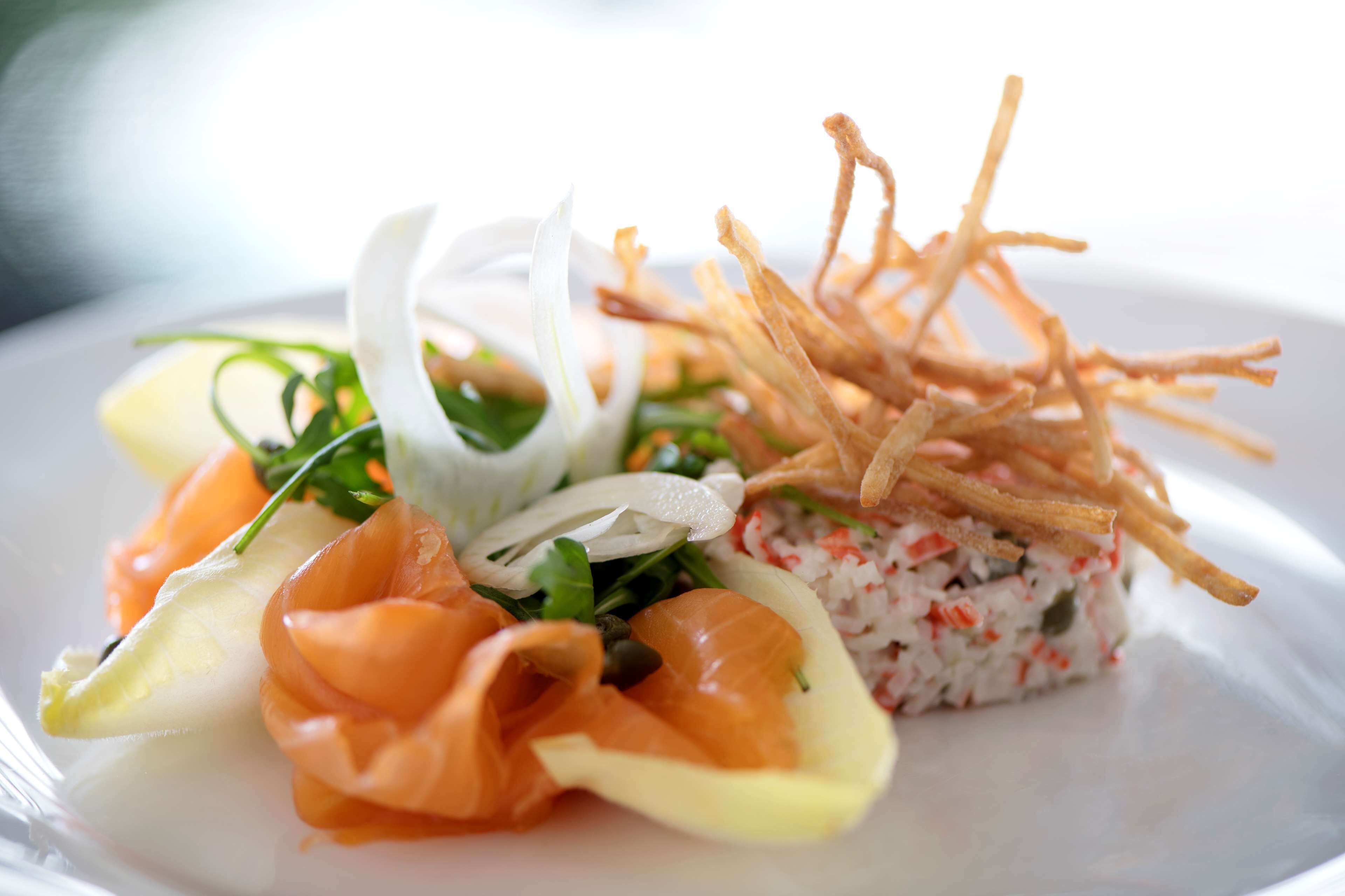 A plate with a salad, salmon, and a rice-based dish.