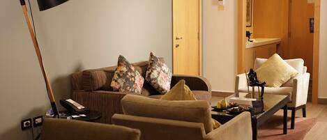 A modern living room with a sofa, armchairs, a coffee table, and a lamp.
