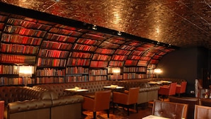 Una biblioteca con estanterías, un sofá de cuero y mesas con menús.