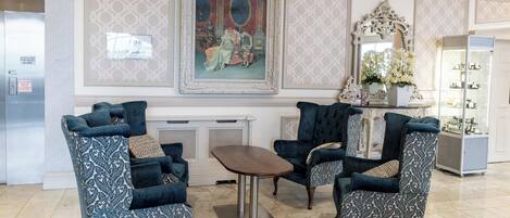 Un hall con tres sillones estampados, una mesita y un espejo decorativo.