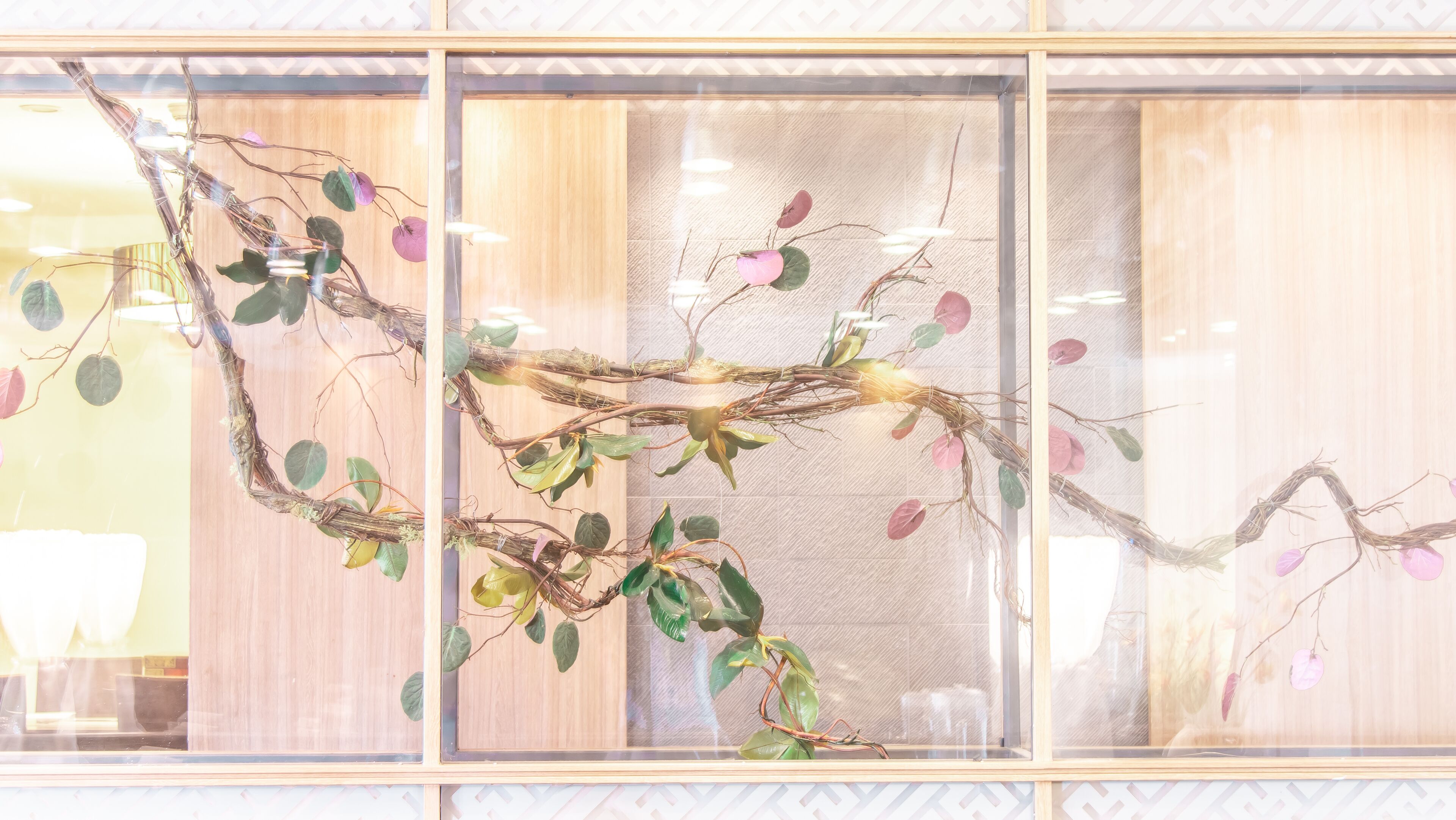 A room with a large window featuring a decorative branch with leaves.