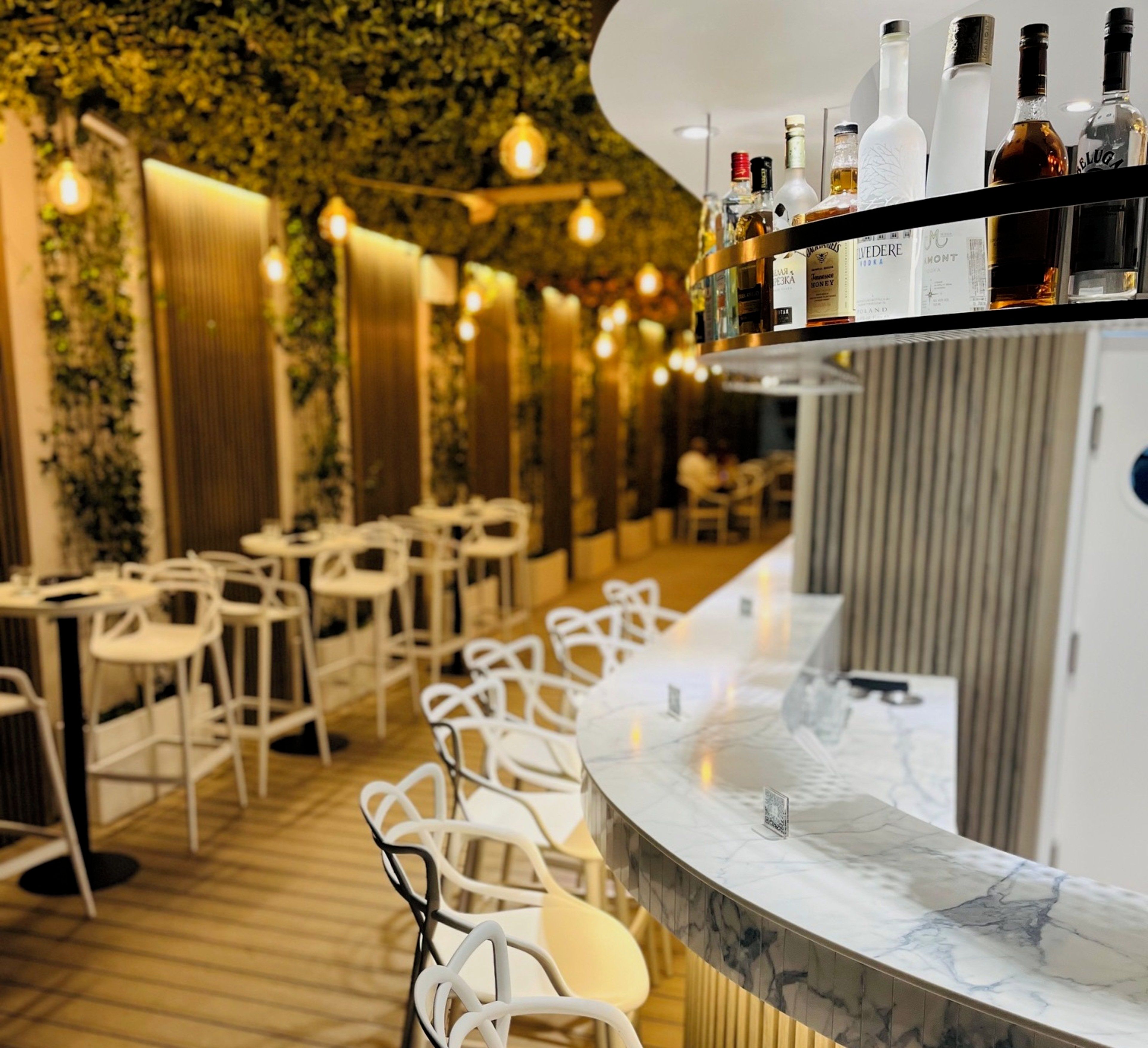 A restaurant interior with a bar area featuring a marble countertop and a variety of liquor bottles.
