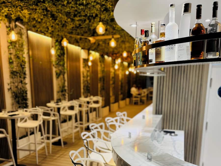 A restaurant interior with a bar area featuring a marble countertop and a variety of liquor bottles.