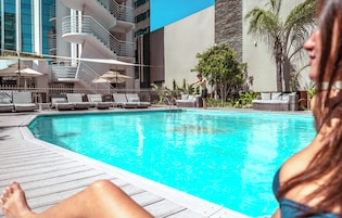 Una piscina con sillas de descanso y un edificio moderno al fondo.