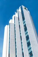 A tall, modern building with a glass facade and a prominent logo at the top.