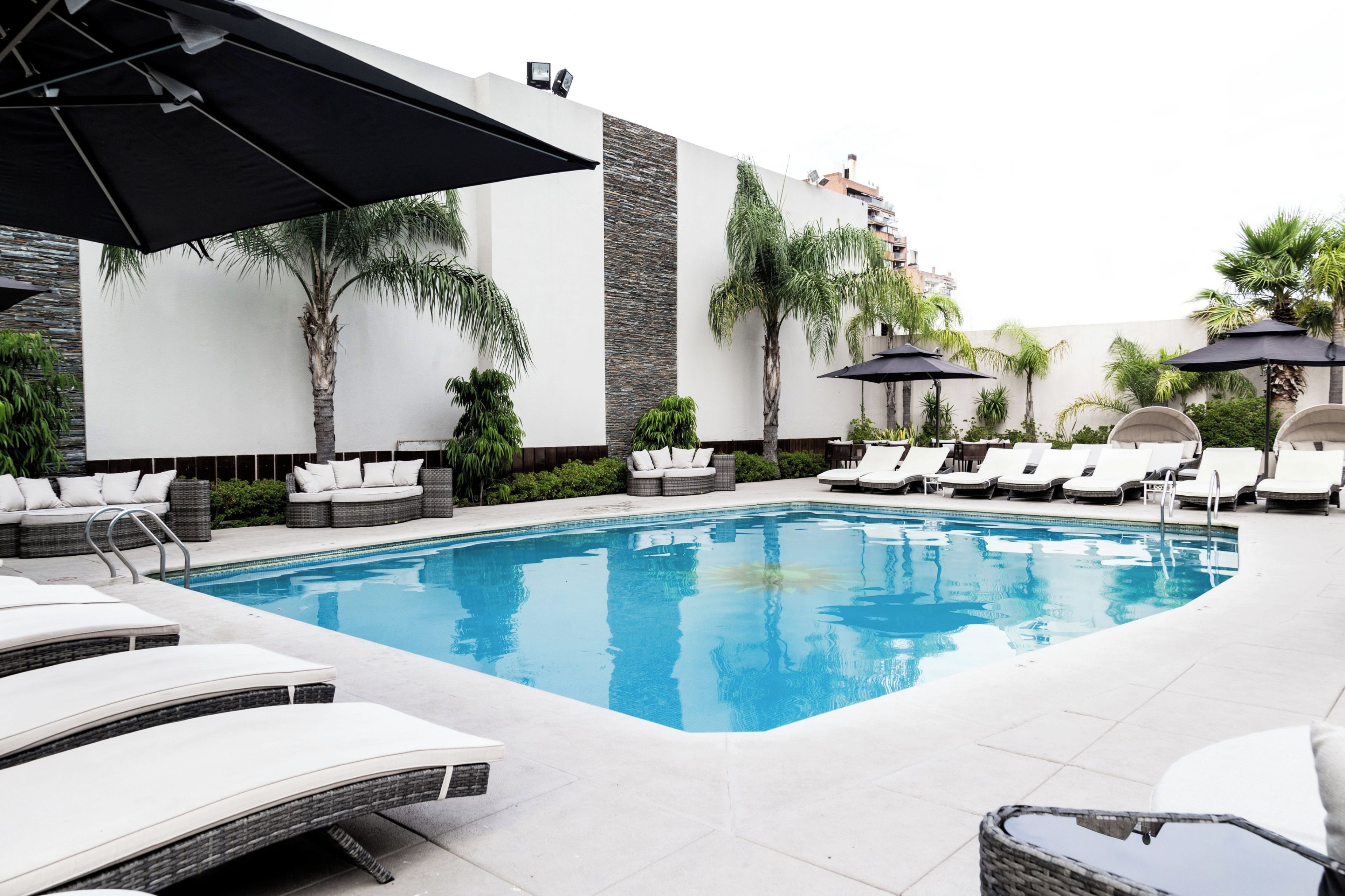 A poolside area with lounge chairs, umbrellas, and a clear blue pool.