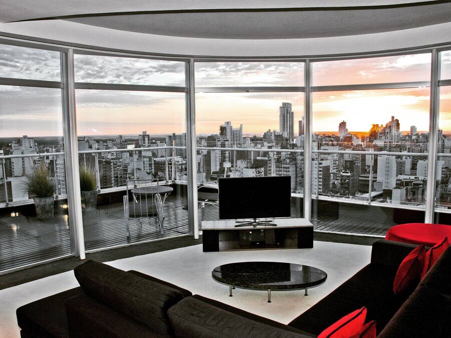 Una sala de estar moderna con un televisor grande, una mesa de centro redonda y un sofá.