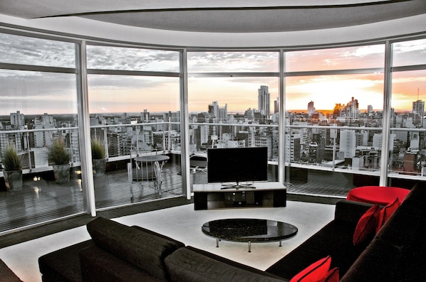 A modern living room with a large TV, a round coffee table, and a sofa. - Holiday Inn Rosario by IHG (Rosario)