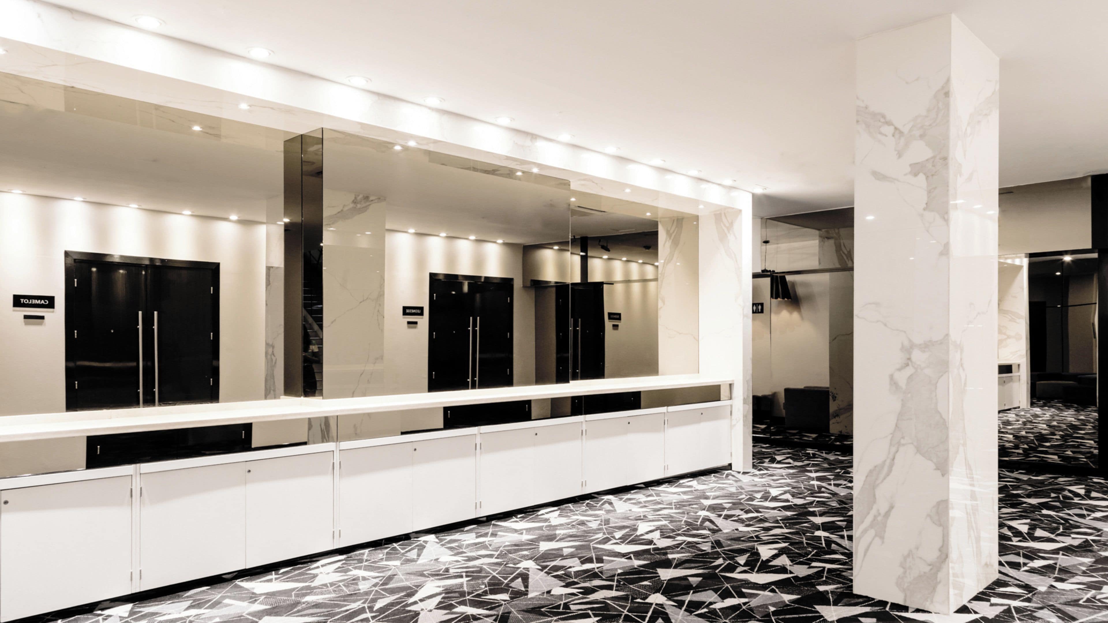 A modern bathroom with a long vanity, mirrors, and a patterned floor.