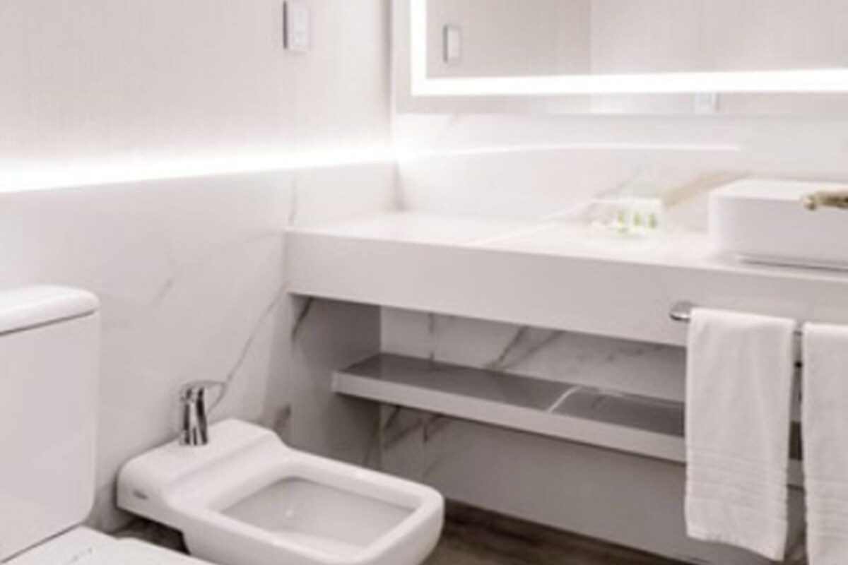 A modern bathroom with a white toilet, bidet, and vanity with a mirror.