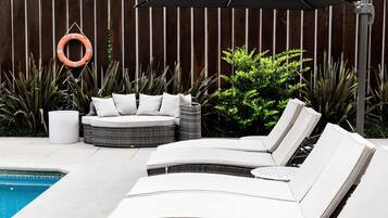 Una piscina al aire libre, sillones reclinables de piscina