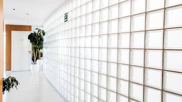 A hallway with a glass wall, potted plants, and a salon exit sign.