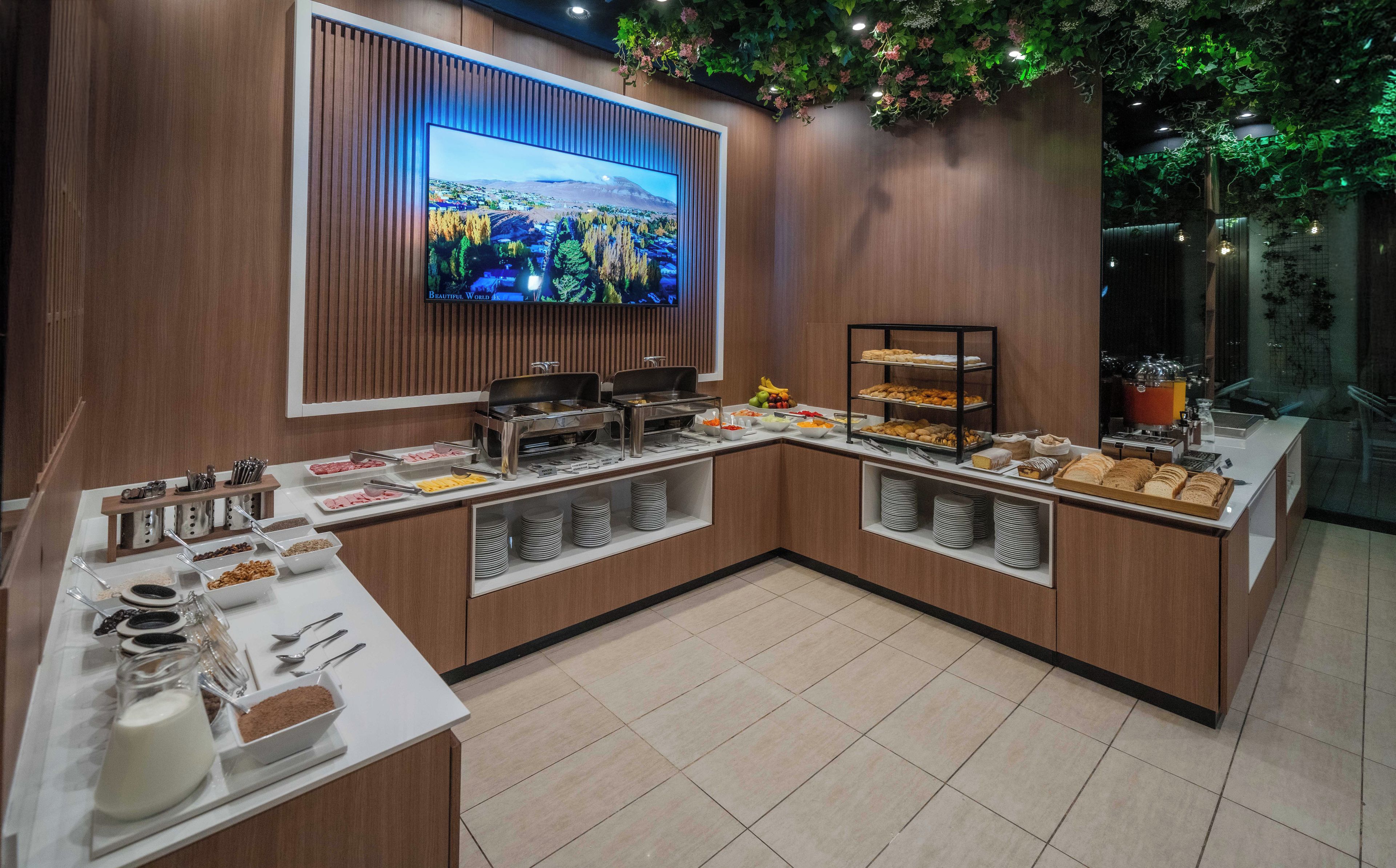 Un'area buffet con diversi piatti e una televisione che mostra un paesaggio panoramico.
