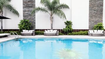 A swimming pool with lounge chairs and palm trees.