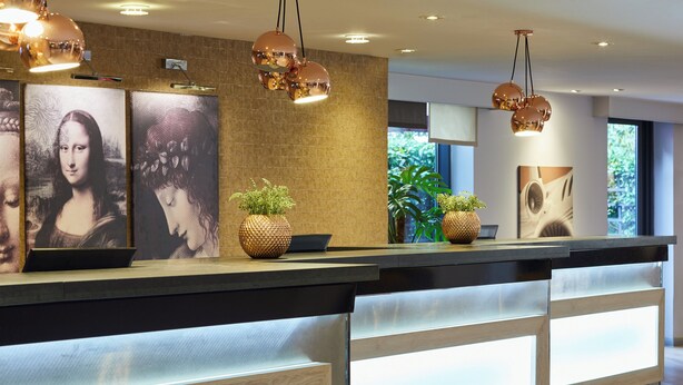 En reception med moderne design, med træfinish, integreret belysning og dekorative elementer som planter og kunstværker.