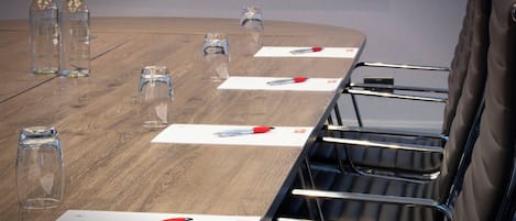 Une table de conférence avec des chaises, des bouteilles d’eau, des verres et des stylos.