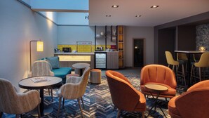 Et moderne loungeområde med højt til loftet, et køkken i baggrunden og et mønstret gulv.