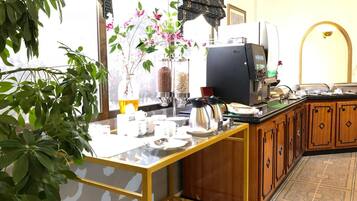 Una cocina con cafetera, planta y ventana con cortinas.