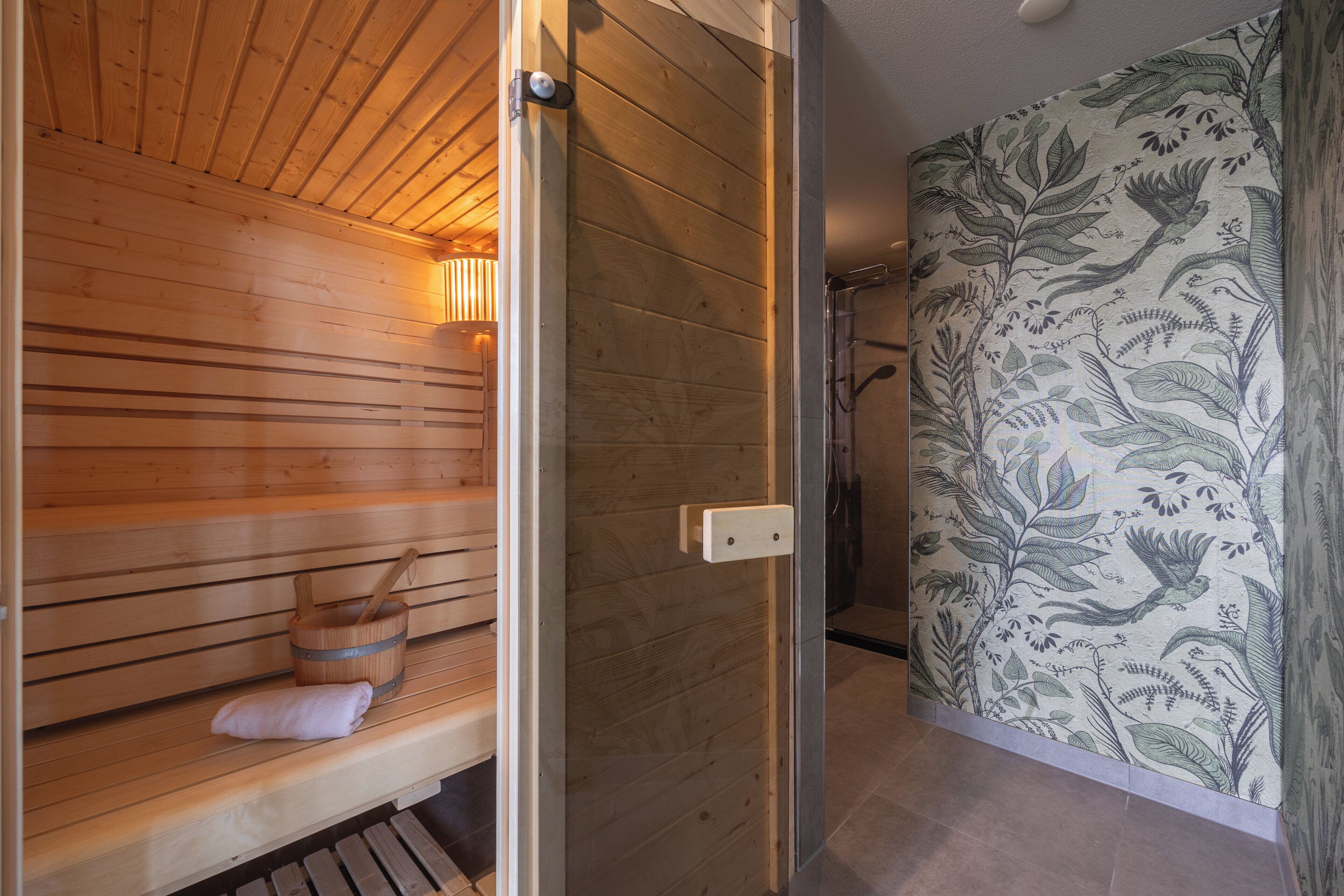 Eine Holzsauna mit Bänken, einem Handtuch, einer Glastür und einer Wand mit Muster.