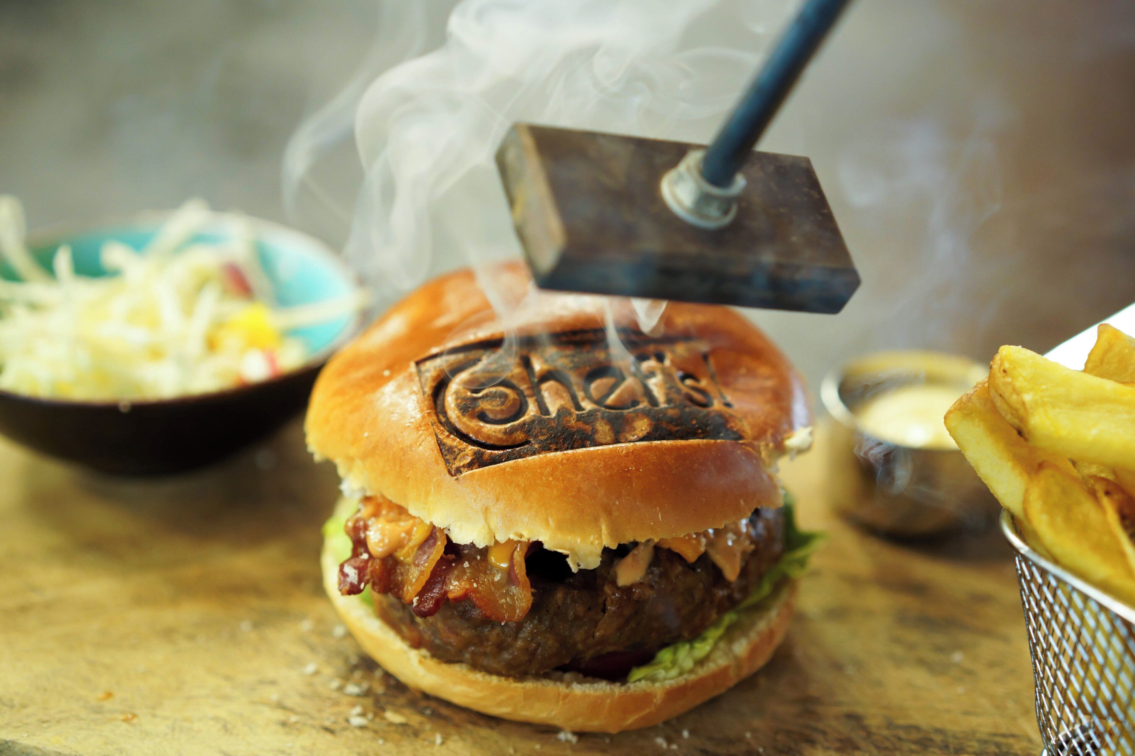 Una hamburguesa con una parrilla encima, una porción de papas fritas y un recipiente pequeño de salsa.