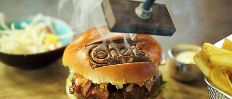 A burger with a grill on top, a side of fries, and a small bowl of sauce.