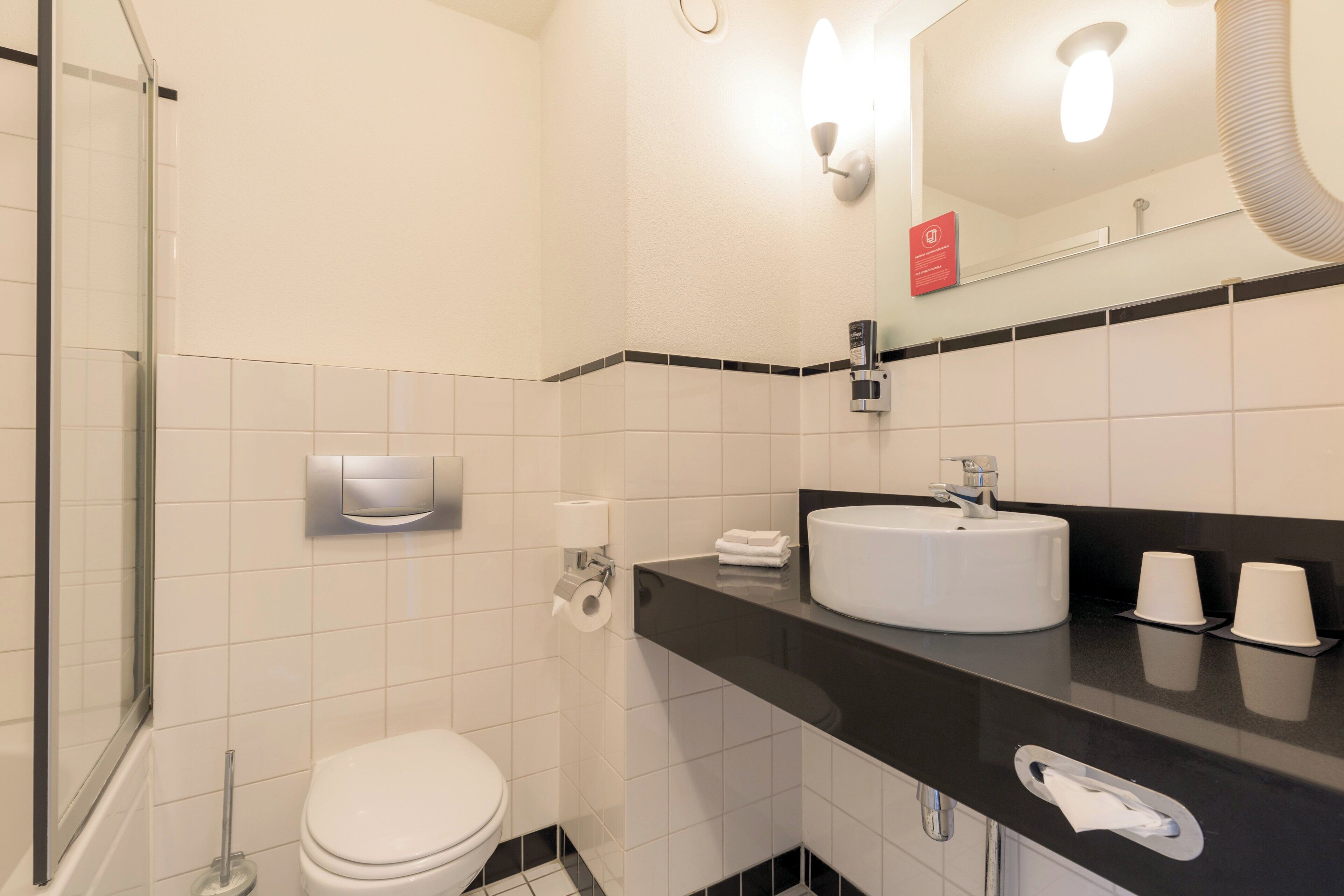 A modern bathroom with a white toilet, a black countertop with a sink, and a mirror above the sink.