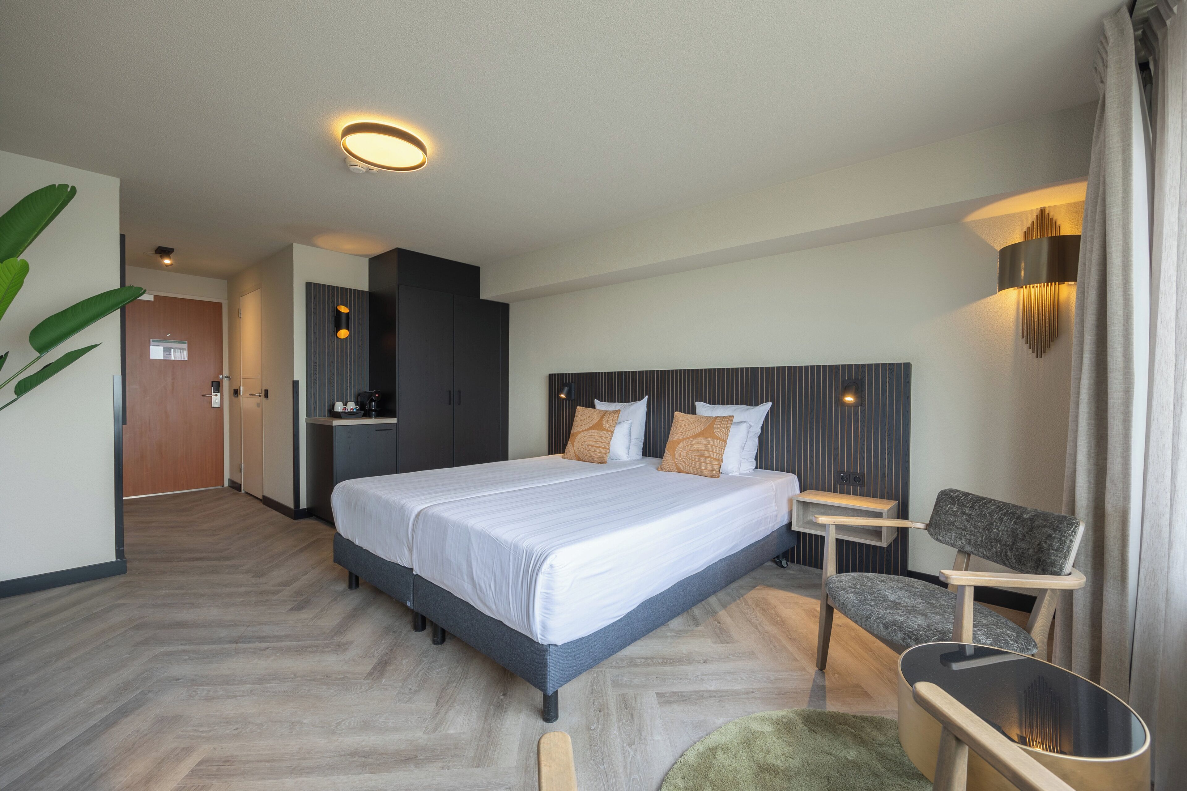 Ett modernt hotellrum med en stor säng, ett skrivbord, en stol och ett litet bord.