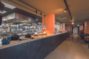 Una cocina moderna con electrodomésticos de acero inoxidable, una encimera amplia y una pared de acento naranja cálida.