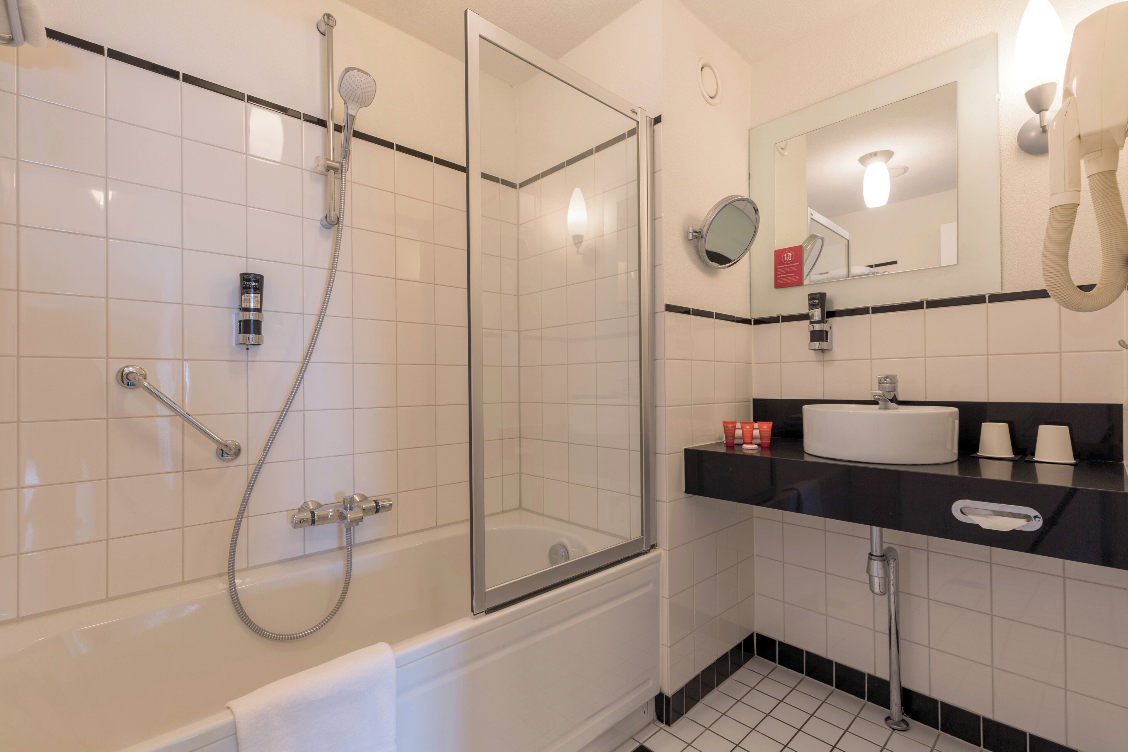 A modern bathroom with a glass-enclosed shower, a bathtub, a sink, and a mirror.